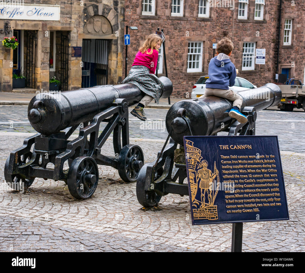 Children sitting on historic old cannons, Broad Street, Stirling Old Town, Scotland UK Stock Photo
