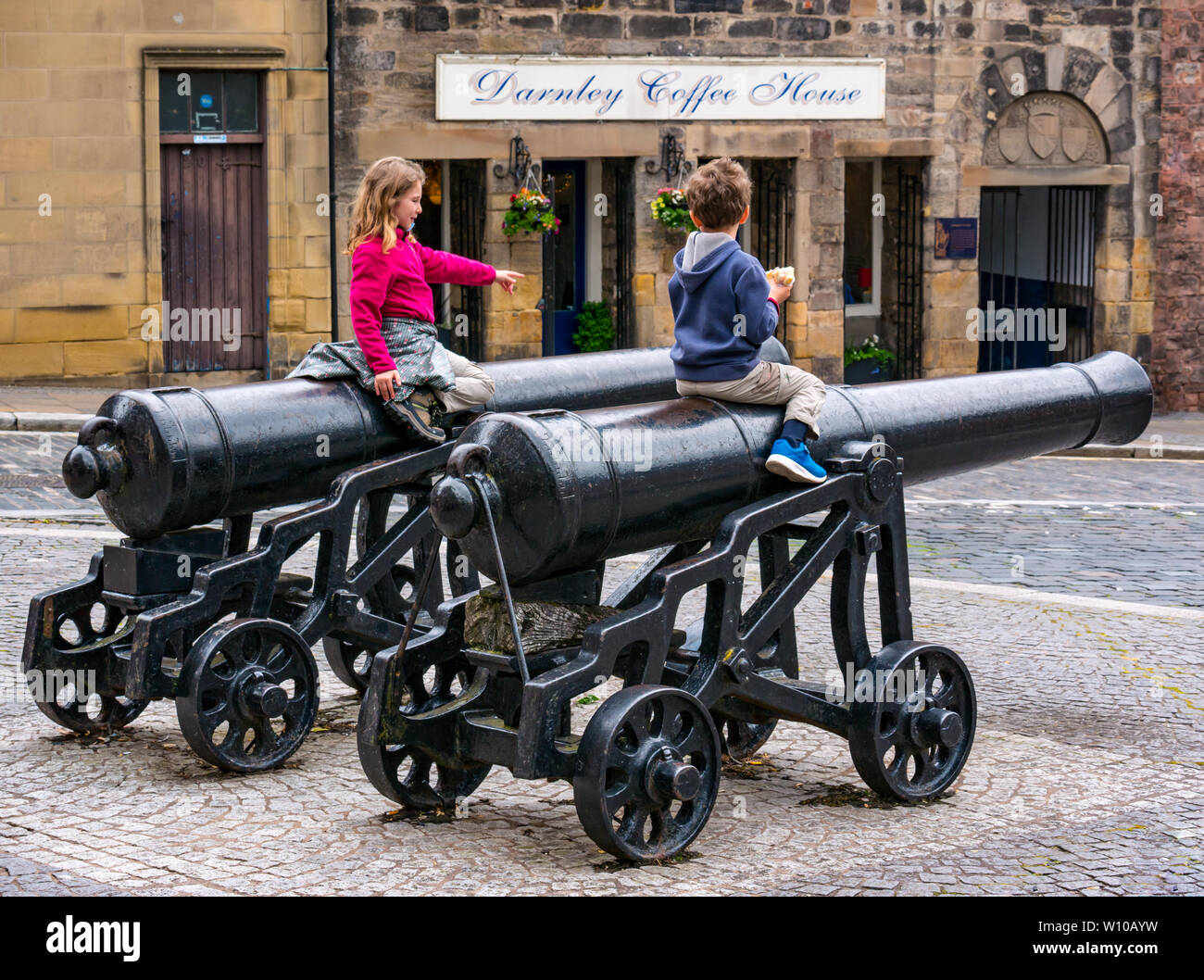 Children sitting on historic old cannons, Broad Street, Stirling Old Town, Scotland UK Stock Photo