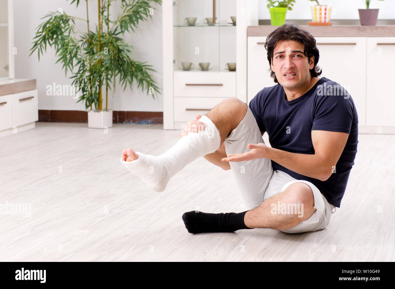 Leg injured young man suffering at home Stock Photo - Alamy