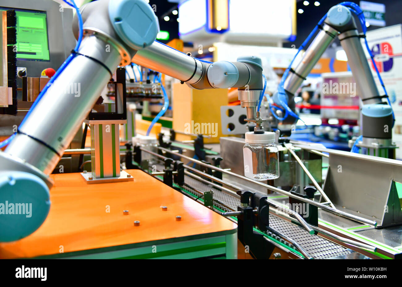 Robot arm arranged glass water bottle on Automatic industrial machinery equipment in production line factory Stock Photo