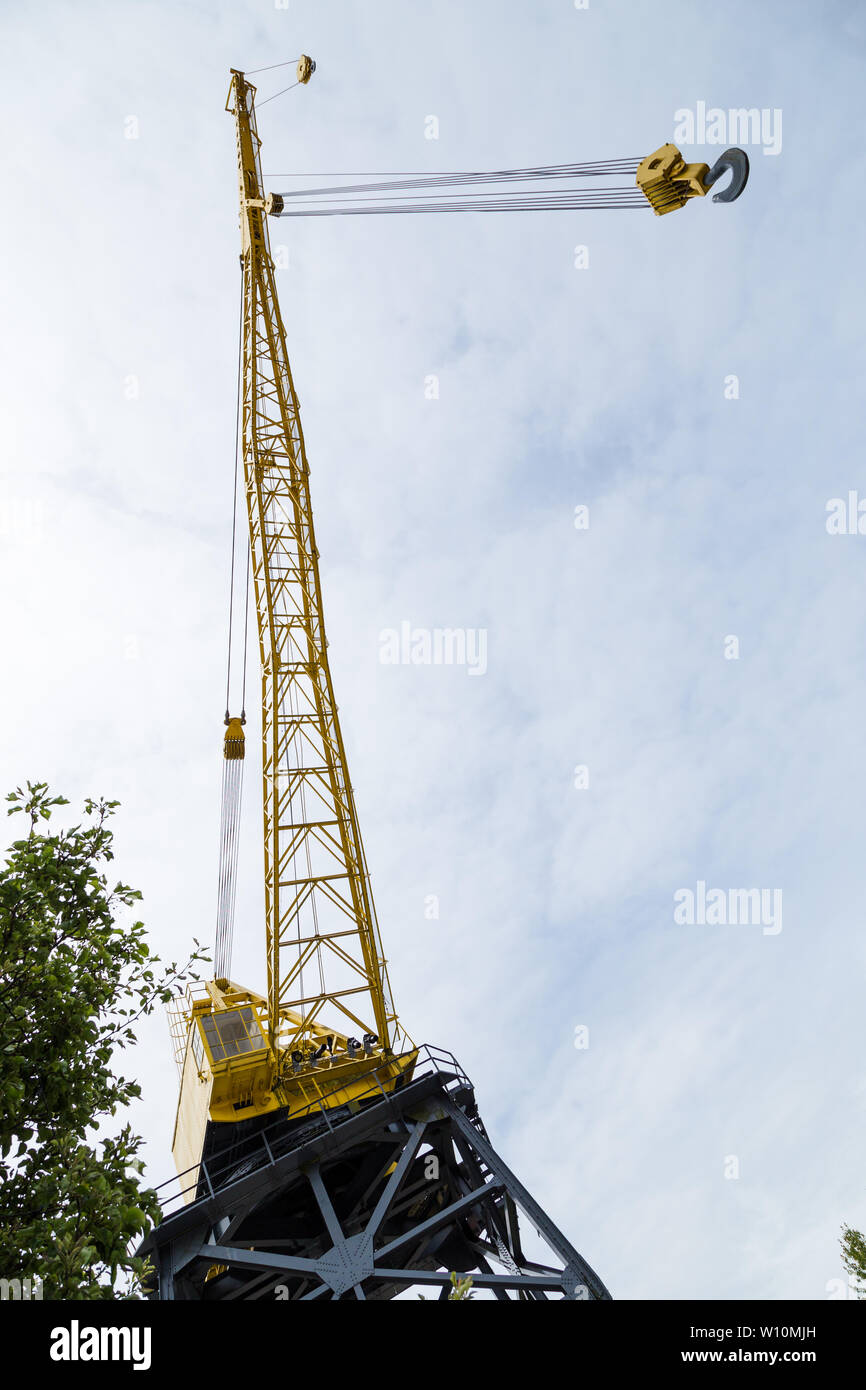 A tall yellow marine construction crane with a hook. Stock Photo