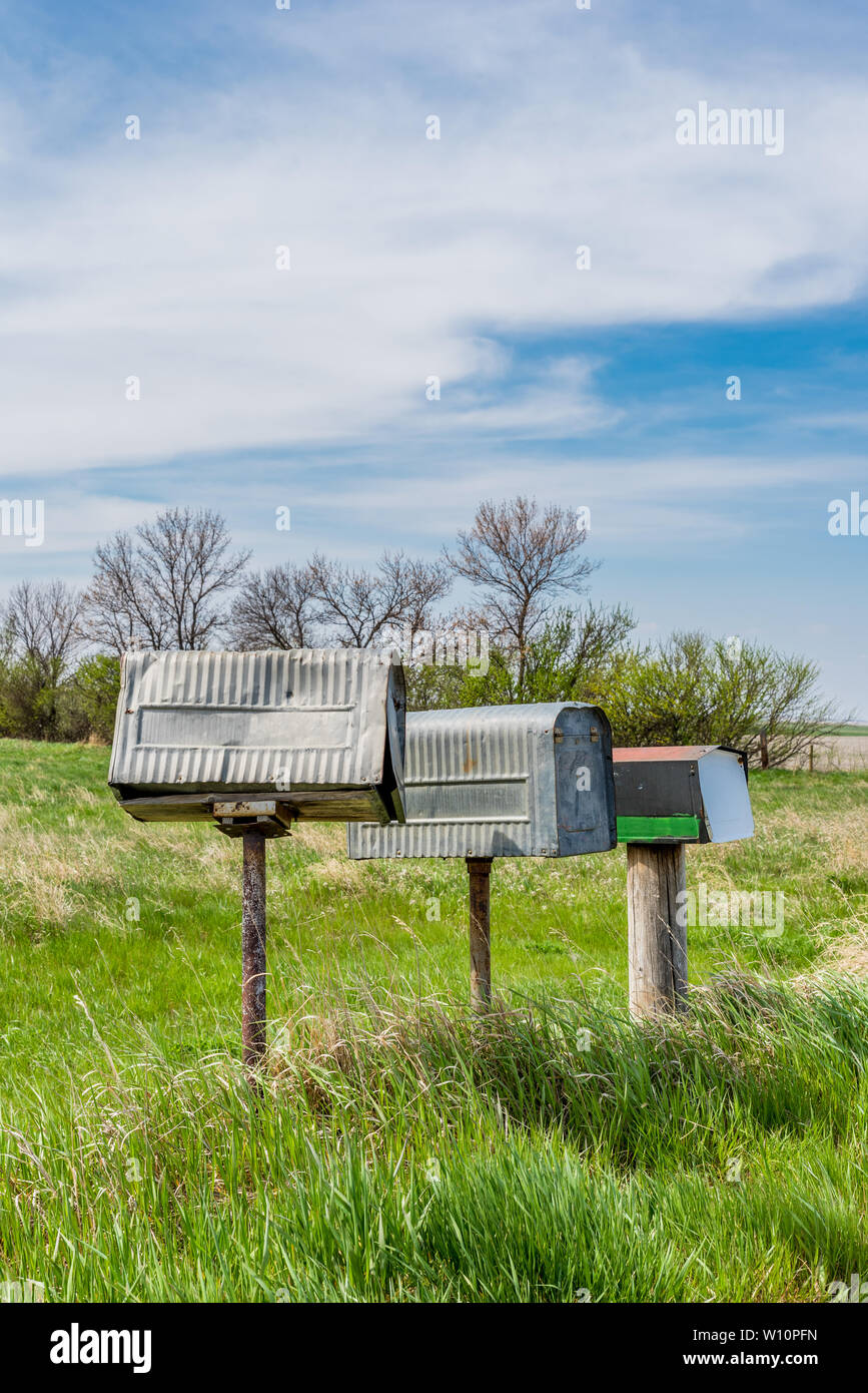 A row of three old metal farmers mailboxes on the prairies in rural