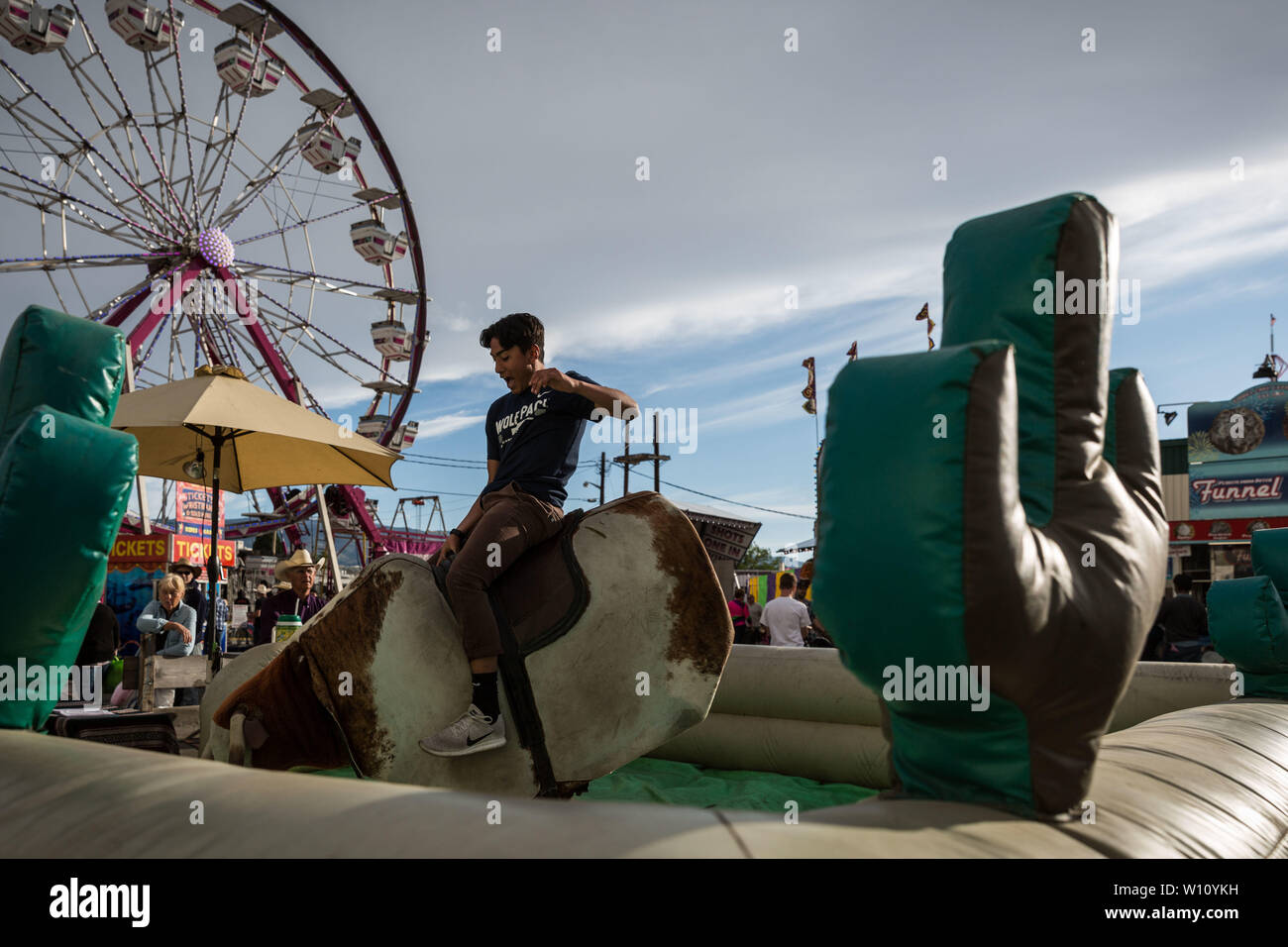 Reno, Nevada, USA. 28th June, 2019. A young man rides a mechanical bull