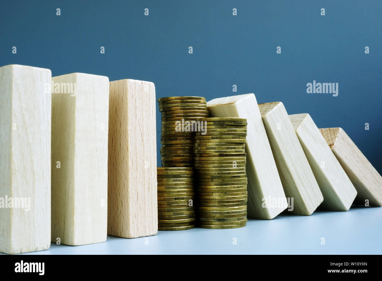 Financial stability concept. Stack of coins and domino effect. Stock Photo