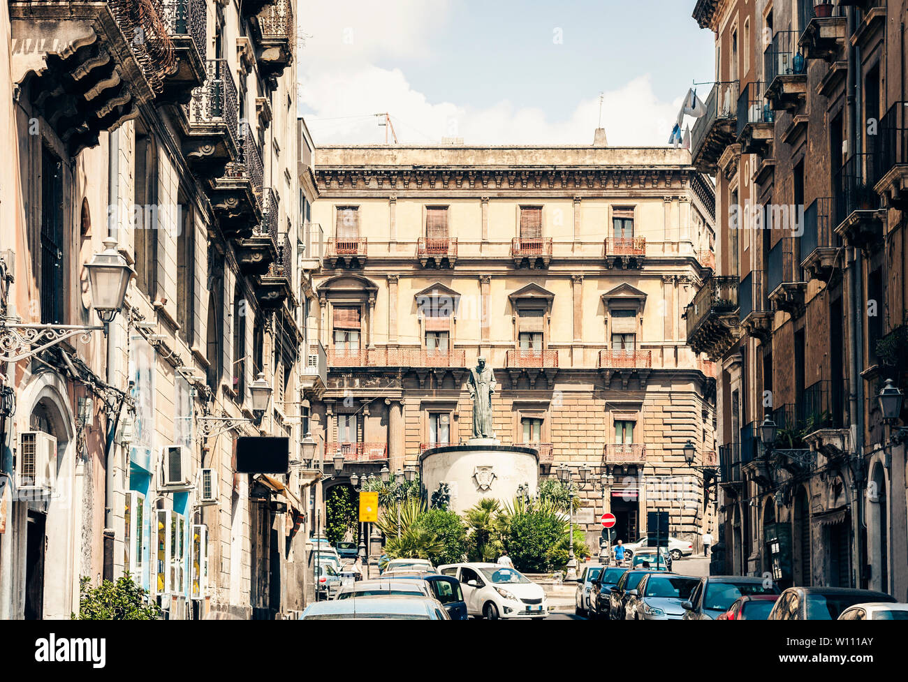 Traditional architecture of Sicily in Italy, typical street of Catania, facade of old buildings with monument of Vincenzo Bellini Stock Photo
