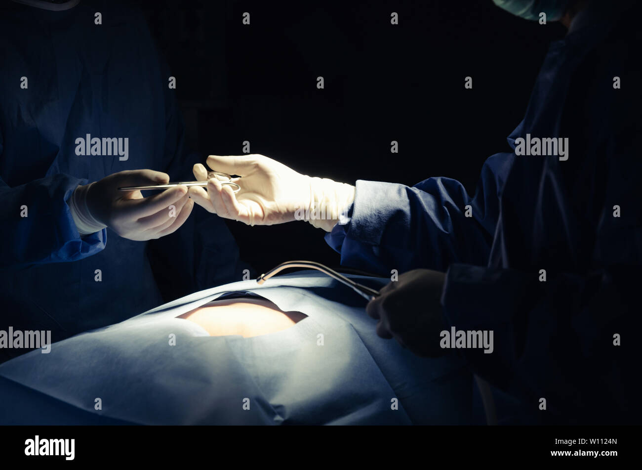 hands of surgeons team sending surgical instrument to partner hand working for rescue patient in operation room at hospital, emergency case, surgery Stock Photo