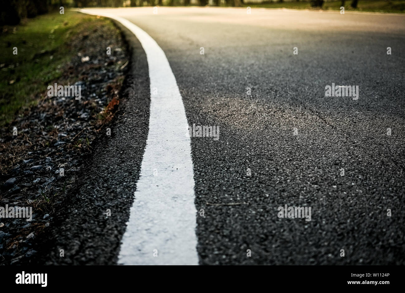 White curve road line on the asphalt floor with soft sun light effect and selective focus, concept of business or travel. Stock Photo