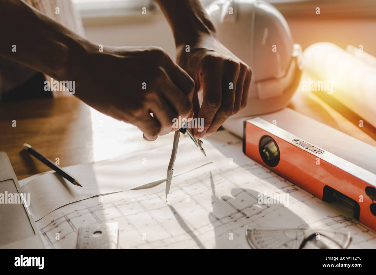 professional architect, engineer or interior hands drawing with divider compass and blueprint on workplace desk in office center at construction site Stock Photo