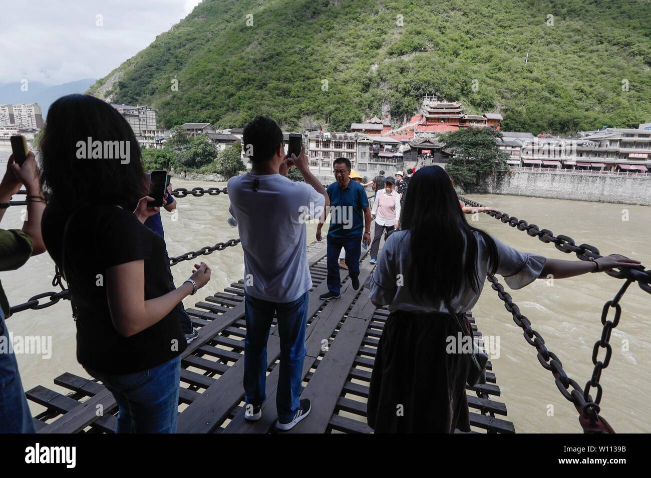 (190629) -- CHENGDU, June 29, 2019 (Xinhua) -- People walk on the iron-chain Luding Bridge across the Daduhe River in Luding County, southwest China's Sichuan Province, June 27, 2019. Along the Sichuan-Tibet Highway, there are various new and old bridges. Crossing mountains and rivers, these bridges are not only the key junctions on this line, but also splendid landscapes. Over the past 60 years, the highway and the bridges along it have been continuously upgraded and perfected, which has become a miniature of the highway traffic development in China. (Xinhua/Jiang Hongjing) Stock Photo