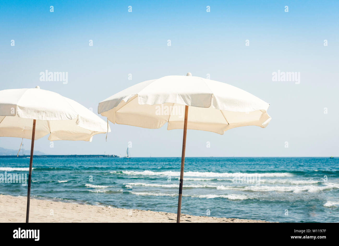 View of the beach of ionic sea near Catania, Sicily, Italy, Lido Cled with white umbrellas . Stock Photo