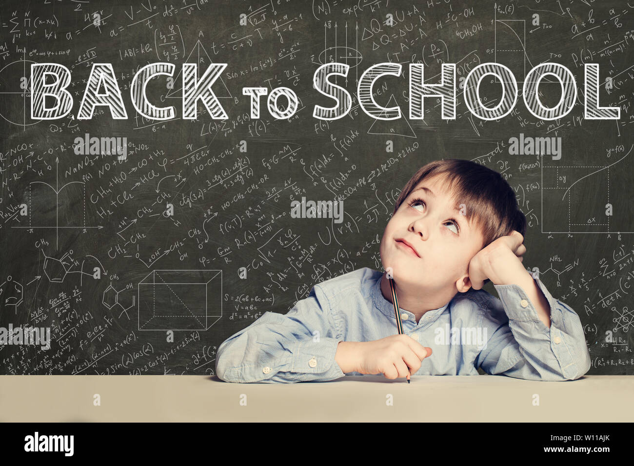 Back to school text and happy kid on chalkboard background Stock Photo