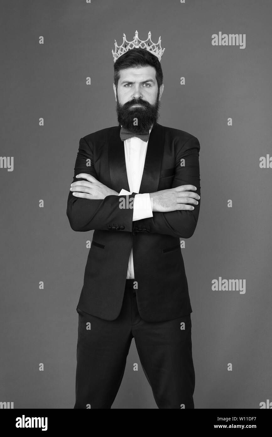 Formal wear male fashion for big boss. Bearded big boss man in tuxedo and bow tie. Egoist. Businessman in tuxedo and crown. Big boss. Formal event. King crown. Man groom in suit. Confident big boss. Stock Photo
