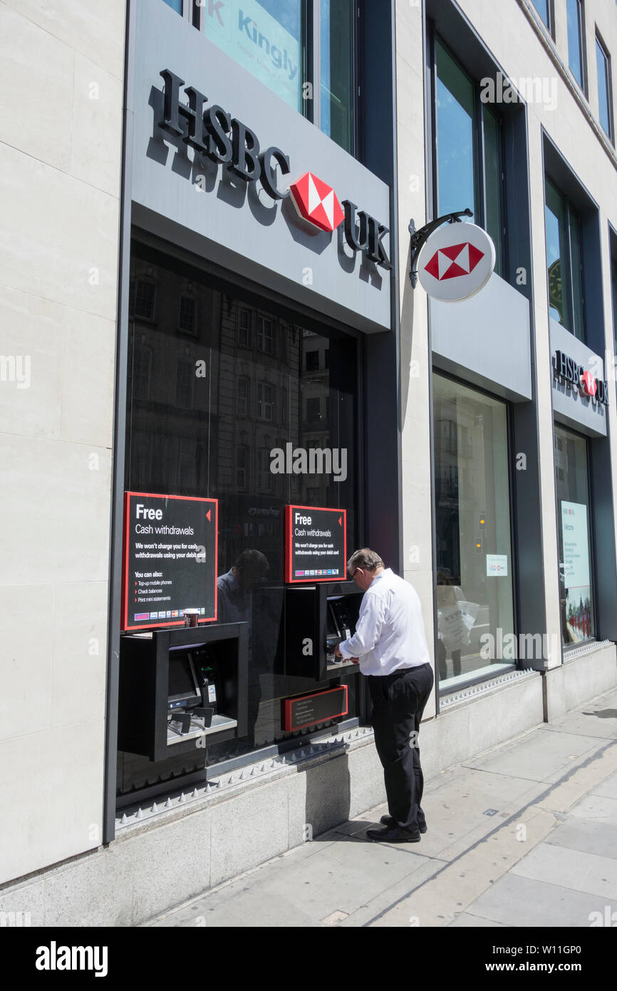 Male customer using ATM outside HSBC branch on Fleet Street, London, UK Stock Photo
