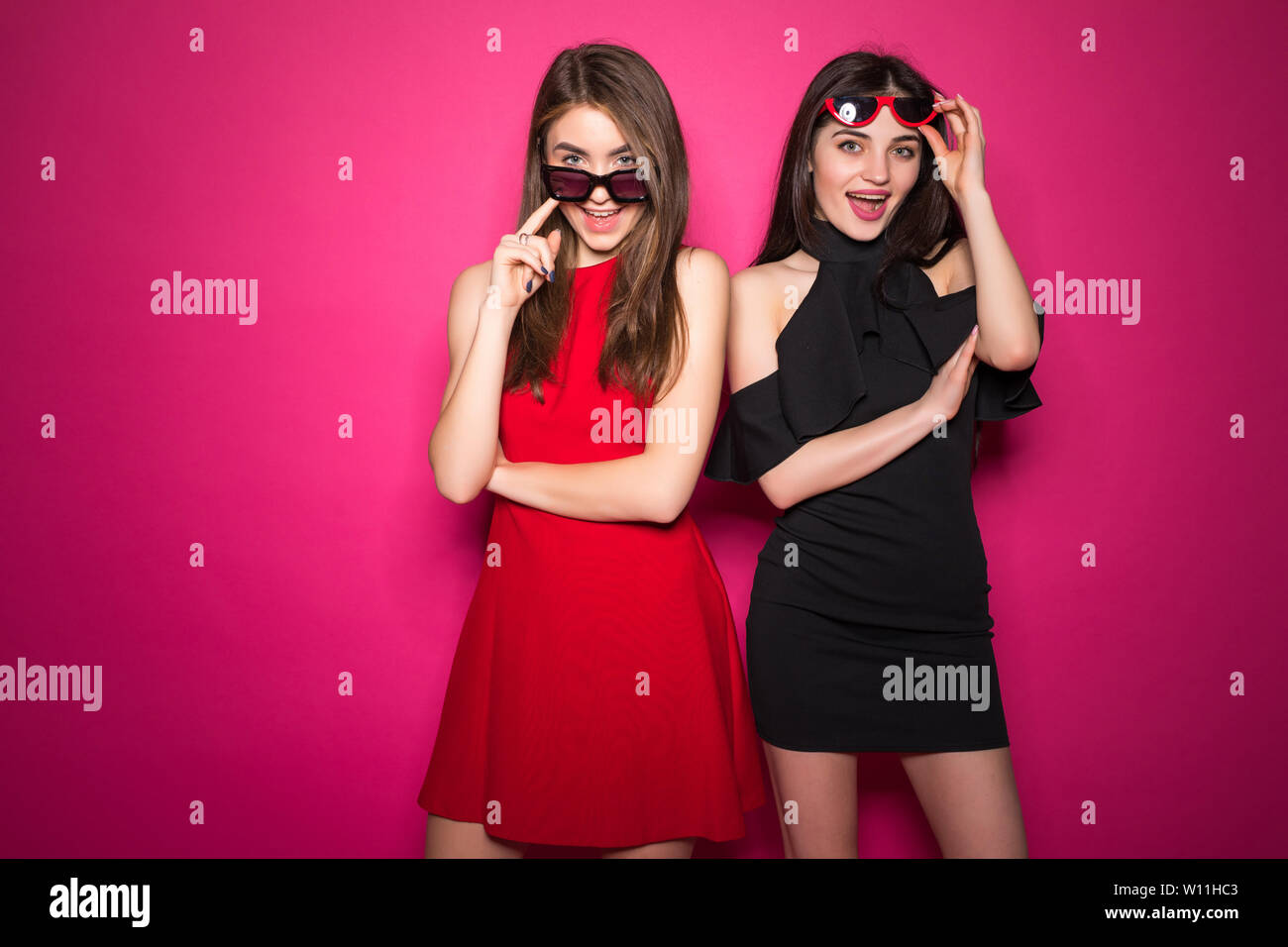 Two Women In Sunglasses And Dress Posing Together And While Looking At The Camera Over Crimson Background Stock Photo Alamy Two Women In Sunglasses And Dress Posing Together And While Looking At The Camera Over Crimson Background Stock Photo Alamy
