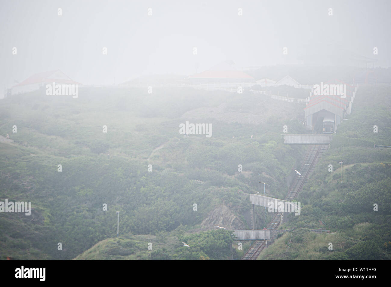 Aberystwyth, Wales, UK. Saturday 29 Jun 2019.  UK weather: As the south east of England is experiencing record breaking hot weather,  the distictive cliff railway in Aberystwyth on  the west coast of Wales is shrouded in low cloud and sea mist, keeping the temperatures substantially cooler.   Photo credit Keith Morris / Alamy Live News Stock Photo