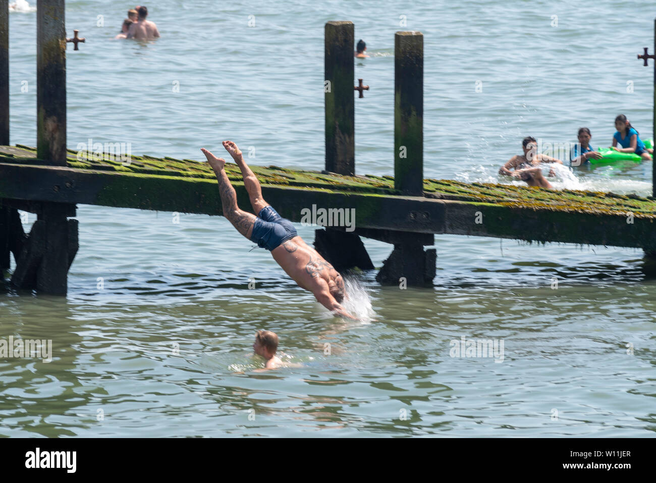 The hot heatwave weather has brought people to Southend to enjoy the beaches, the Estuary, with a male diving in to the Thames Stock Photo
