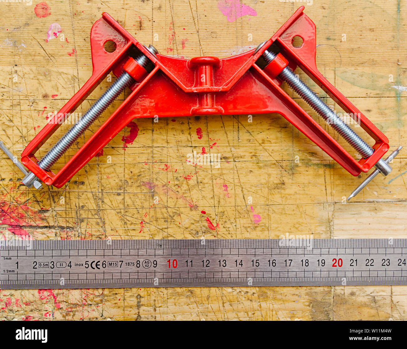 Angle Clamp And Ruler On Red Paint Stained Wooden Workbench