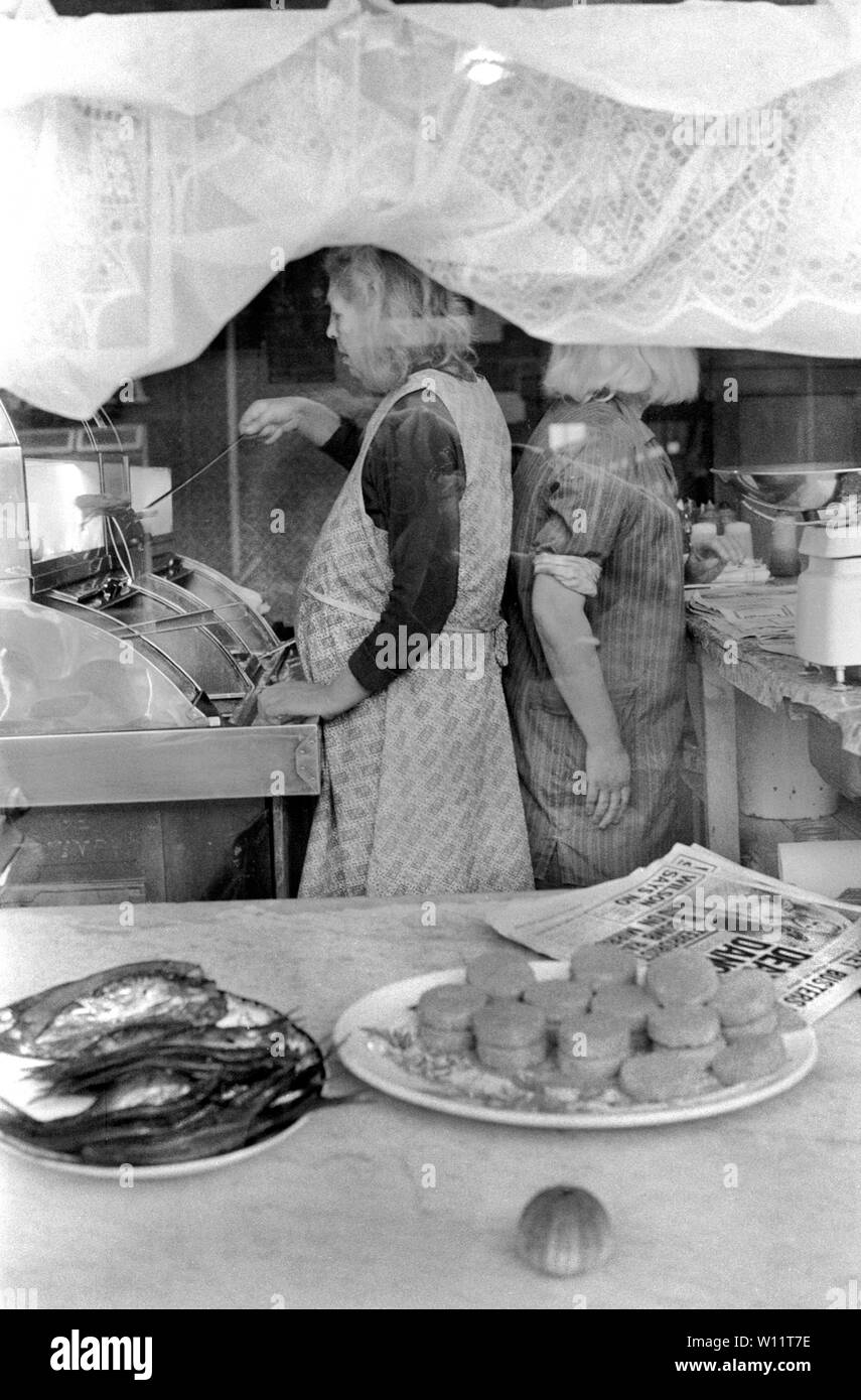 Fish and chip shop window two women working frying fish, chips and ...