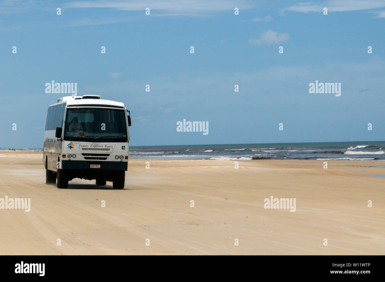 A tourist tour bus on the two lane 75 mile long Sandy Highway facing the South Pacific Ocean on Fraser Island in Queensland, Australia.    Fraser Isla Stock Photo