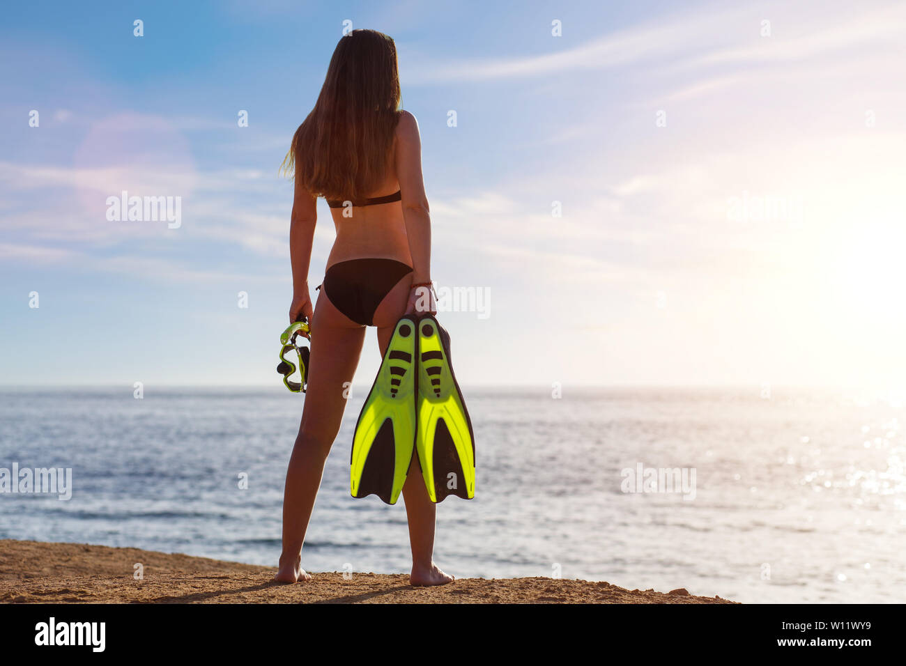 Young beautiful girl standing with snorkel and flippers near the sea. Tropical vacation snorkelling background with copy space Stock Photo