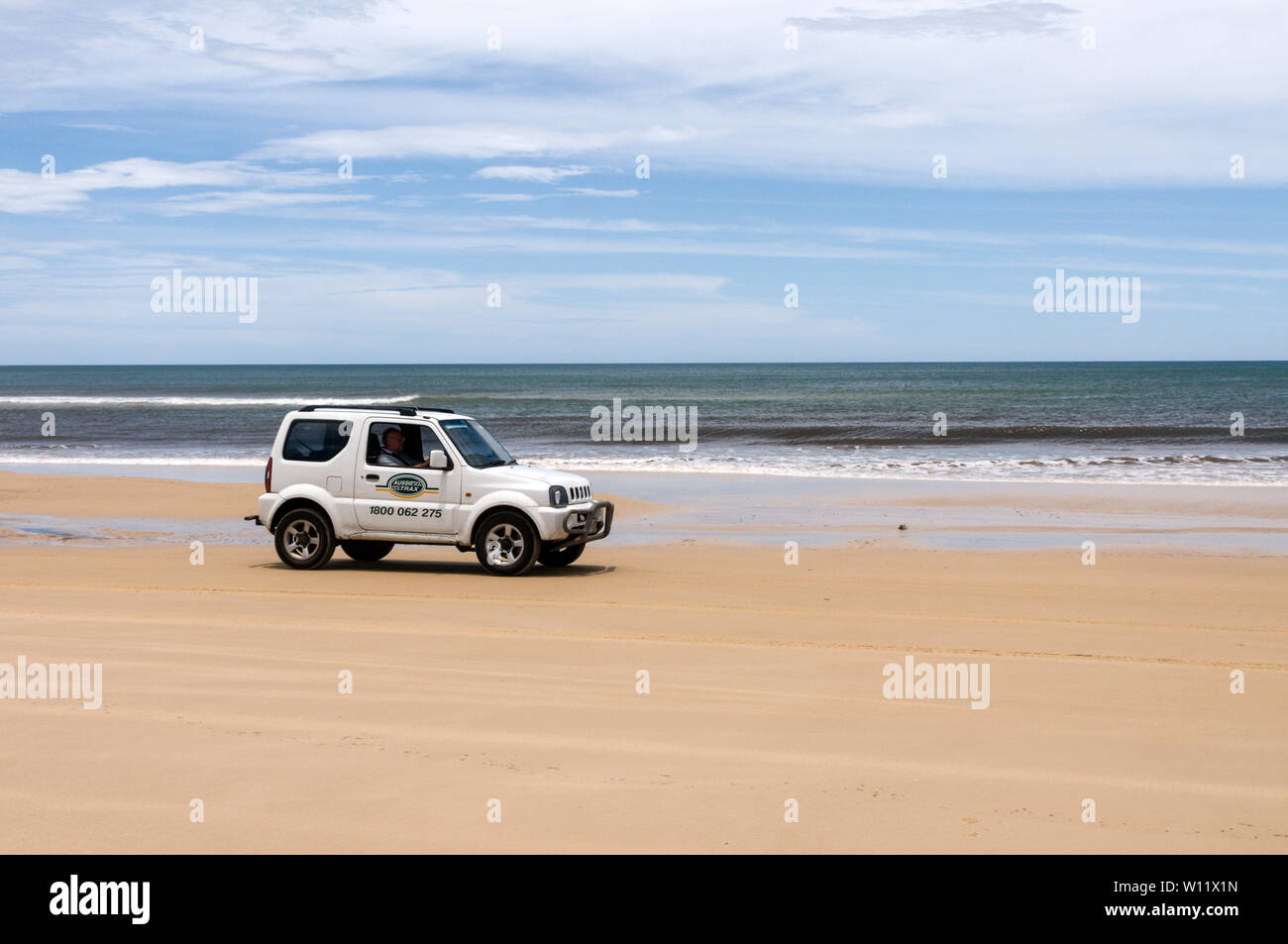 A Suzki Jimmy crossing the wide sandy beach on the 75 mile long Sandy Highway opposite the Coral Sea on Fraser Island, Queensland, Australia  Fraser I Stock Photo
