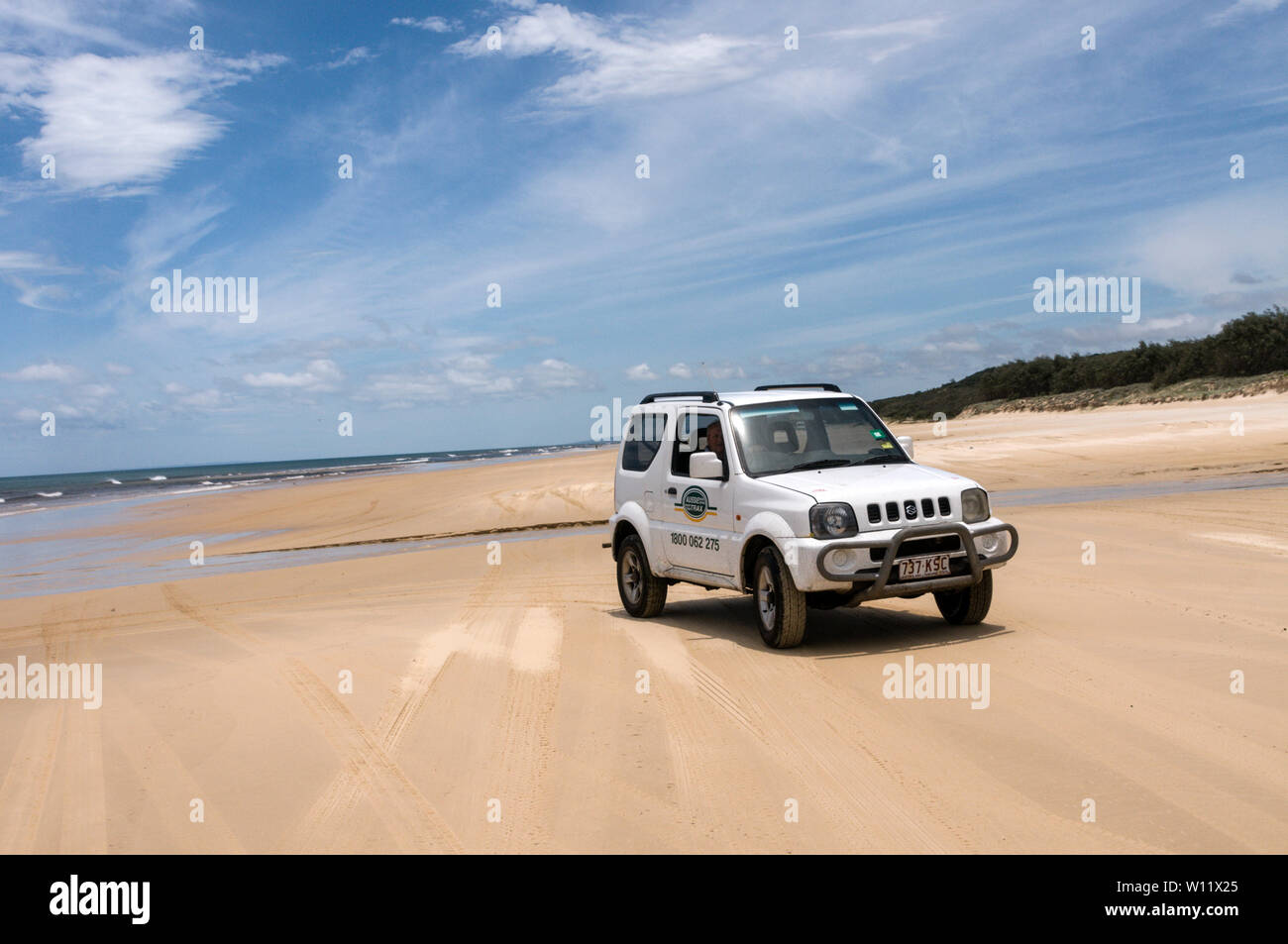 A Suzki Jimmy crossing the wide sandy beach on the 75 mile long Sandy Highway opposite the Coral Sea on Fraser Island, Queensland, Australia  Fraser I Stock Photo
