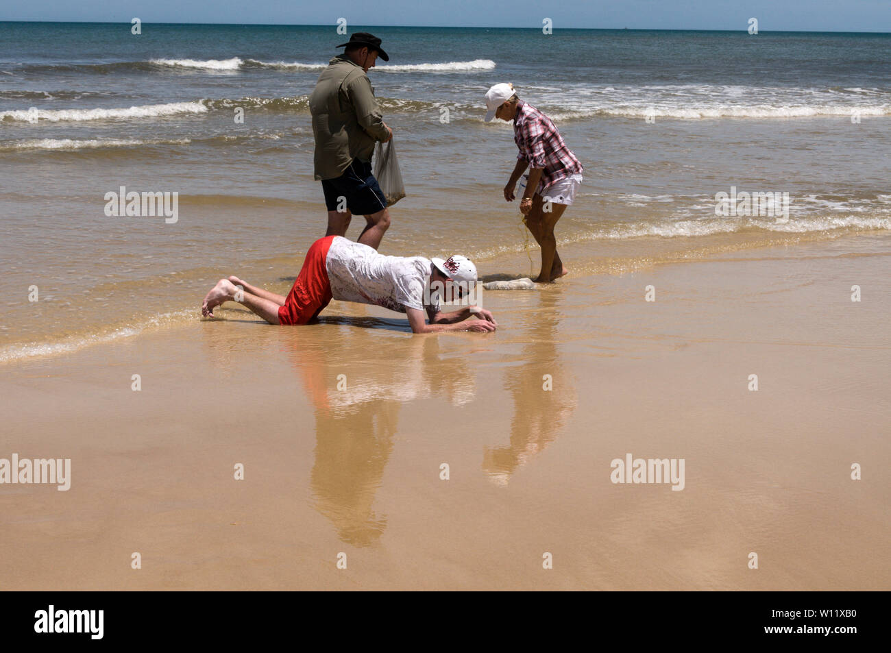 Two men and a woman searching for sea worms used  for fishing bait along the 75 mile Sandy Highway on Fraser Island, Queensland,Australia. Stock Photo
