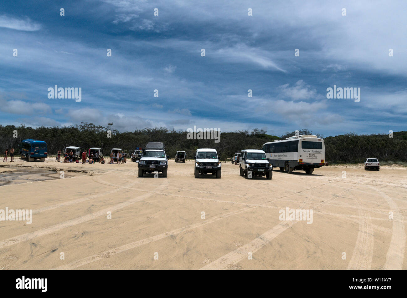 A large group of young backpackers and their vehicles on the 75 mile long Sandy Highway on the east coast of Fraser Island in Queensland, Australia  F Stock Photo