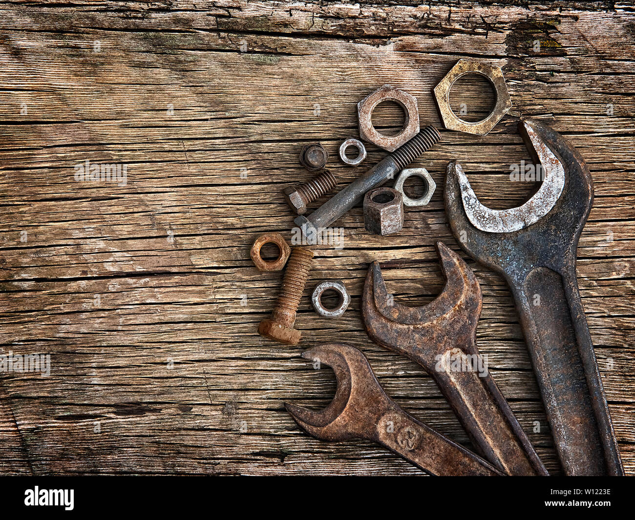 Old wrenches on the nuts and bolts on a wooden grungy background Stock Photo