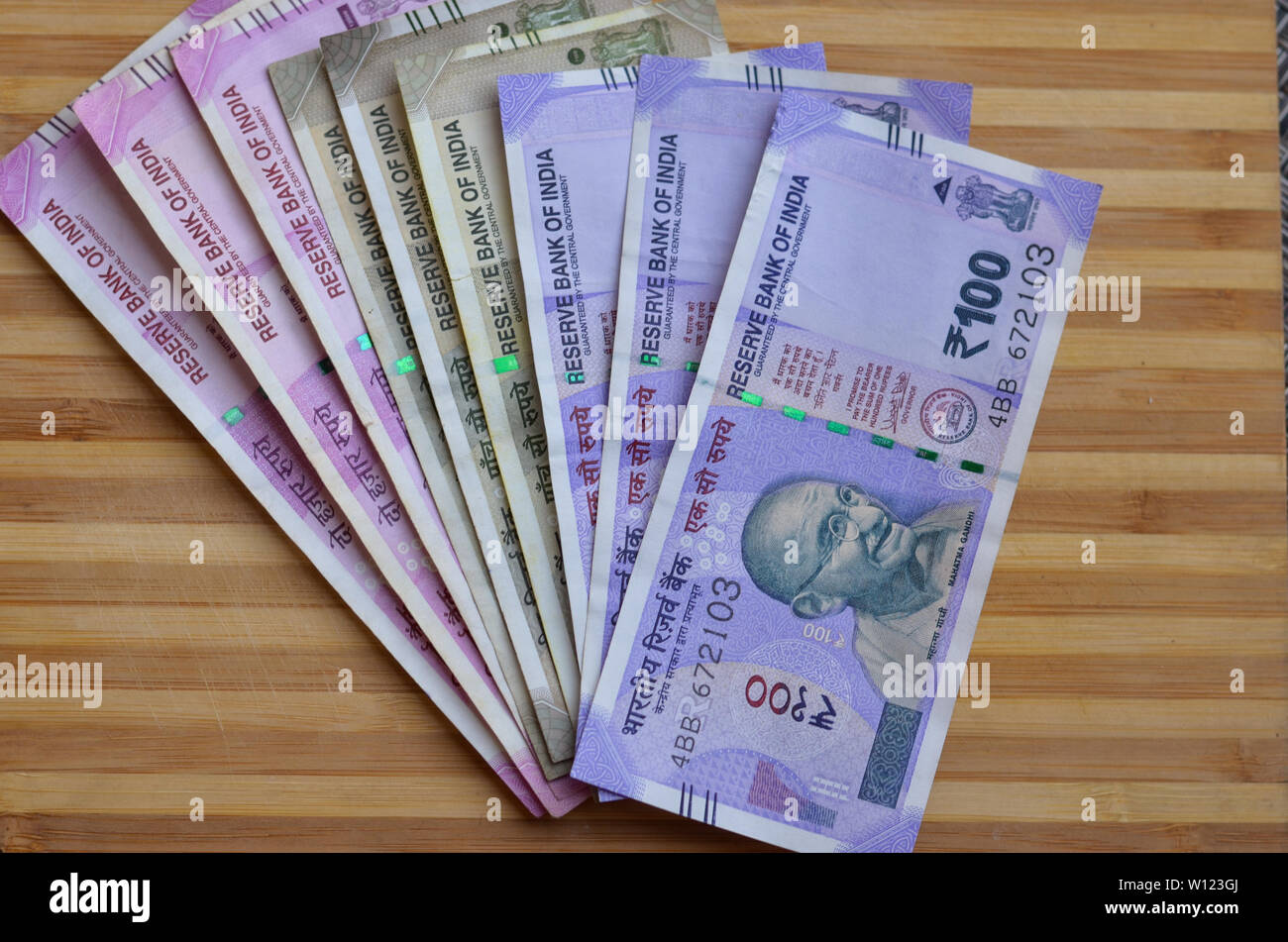 Closeup of new colorful Indian currency bank notes of 10, 50,100, 500 & 2000 rupees bundle issued and in circulation after demonetisation against wood Stock Photo