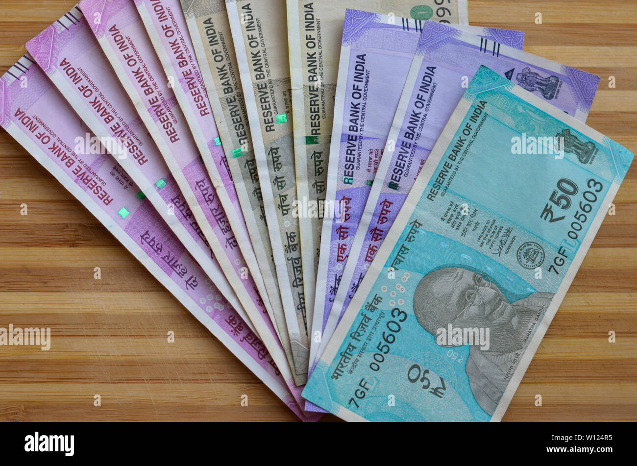 Closeup of new colorful Indian currency bank notes of 10, 50,100, 500 & 2000 rupees bundle issued and in circulation after demonetisation against wood Stock Photo