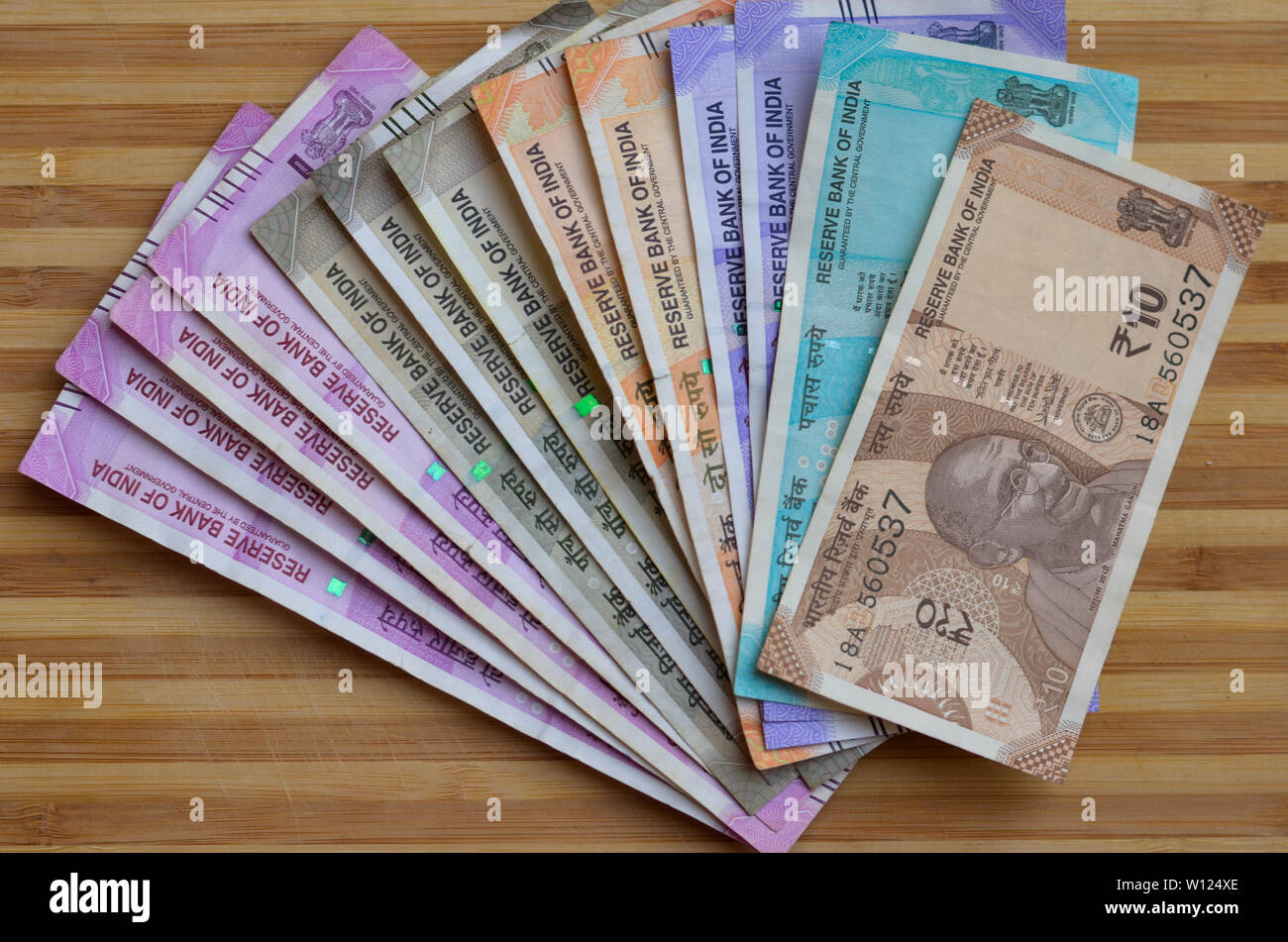 Closeup of new colorful Indian currency bank notes of 10, 50,100, 500 & 2000 rupees bundle issued and in circulation after demonetisation against wood Stock Photo