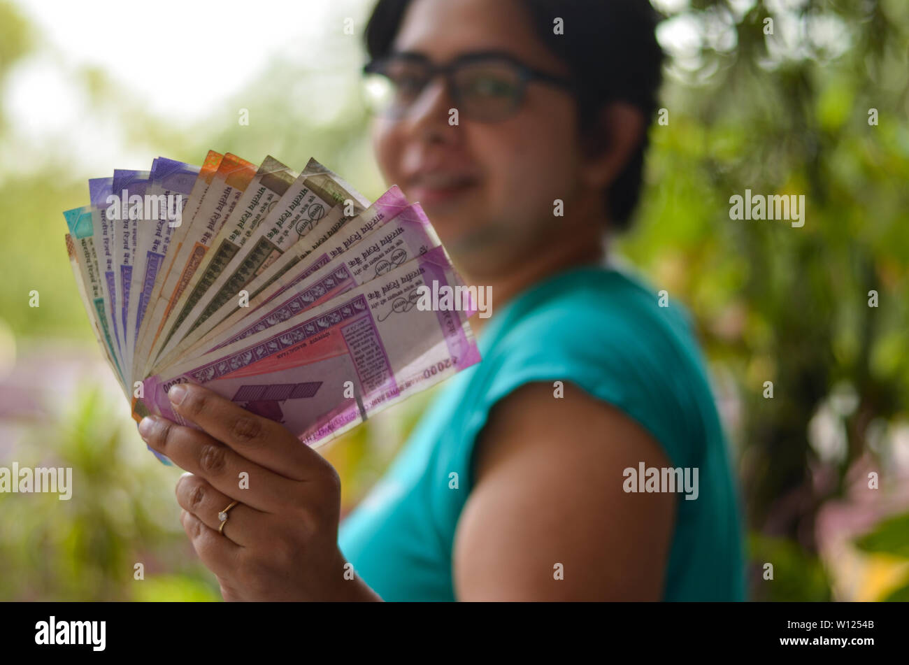 An Indian women holding all the colorful new released Indian Rupees currency notes after demonetisation in denominations Stock Photo