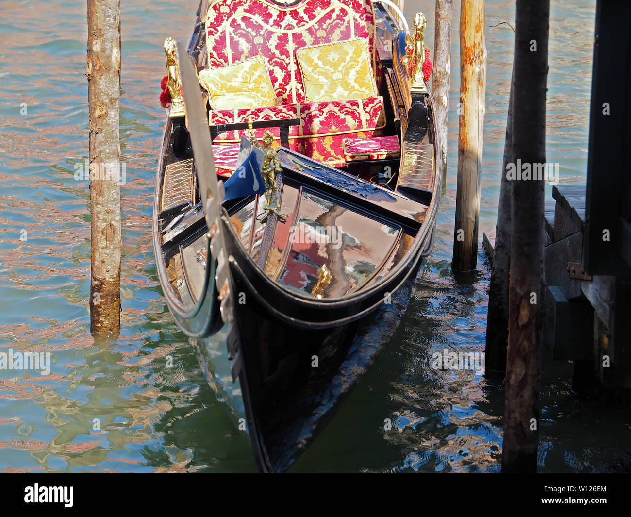 Gondola in Venice in Italy with cozy seats, ornaments, statues and ...