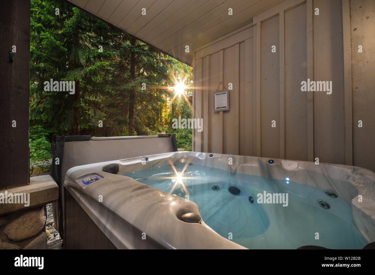 A outdoor hot tub near a forest with a sunburst coming through the trees Stock Photo Alamy