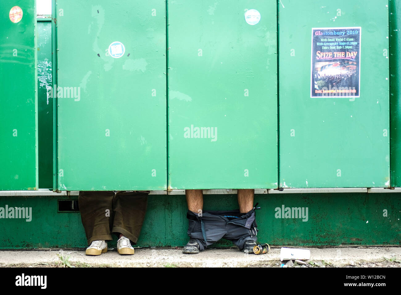 Glastonbury, Somerset, UK. 29th June, 2019. Feet under the green doors of the toilets at Glastonbury Festival 2019 on Saturday 29 June 2019 at Worthy Farm, Pilton. Picture by Credit: Julie Edwards/Alamy Live News Stock Photo