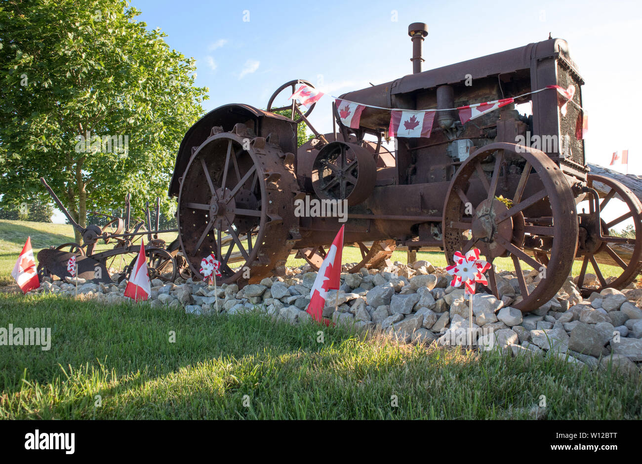 In the countryside, a antique Mc Cormick-Deering tractor bordered with the Canadian flags. The Canada Day. Stock Photo