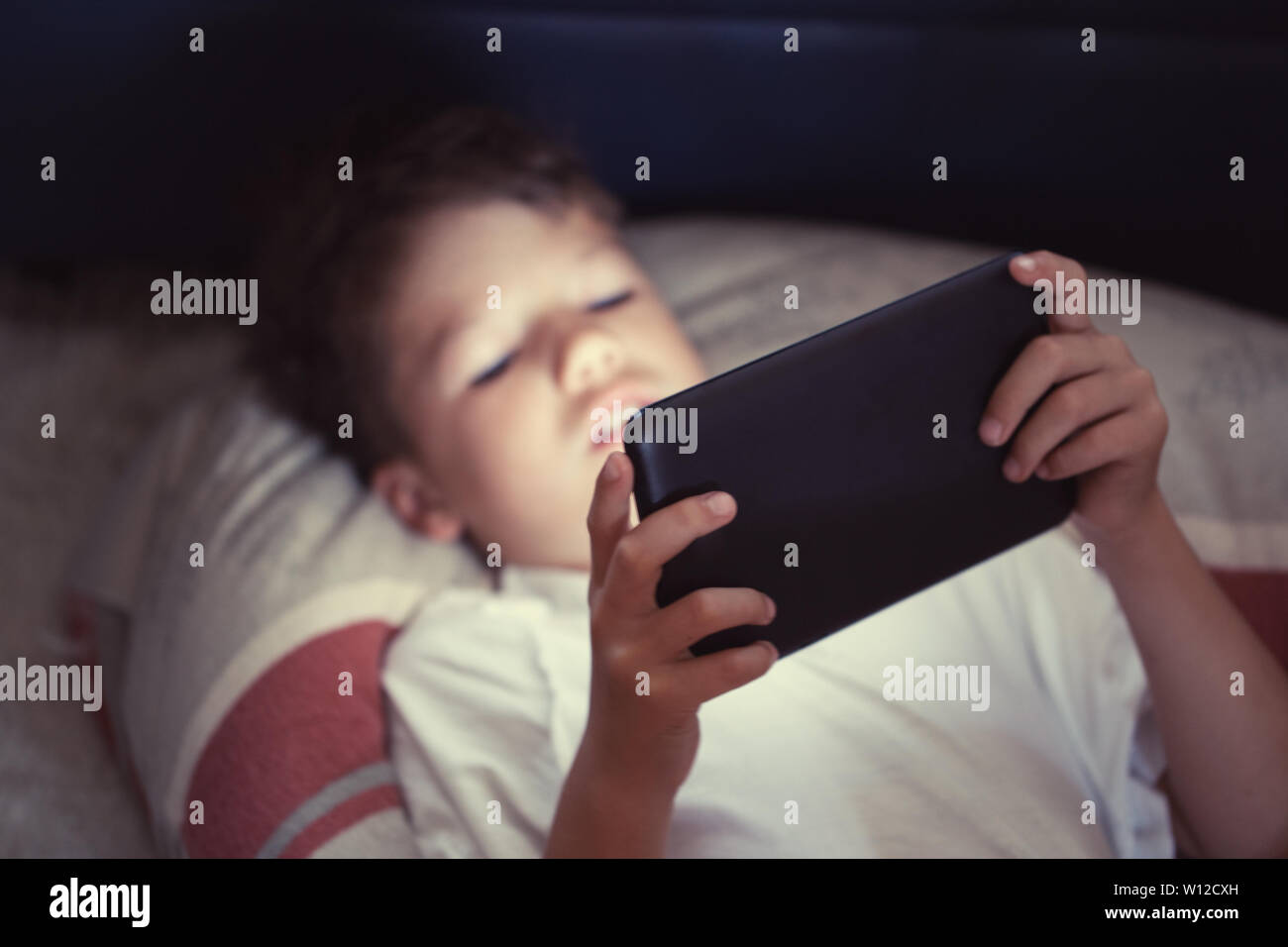 Little boy using digital tablet at night in bedroom Stock Photo