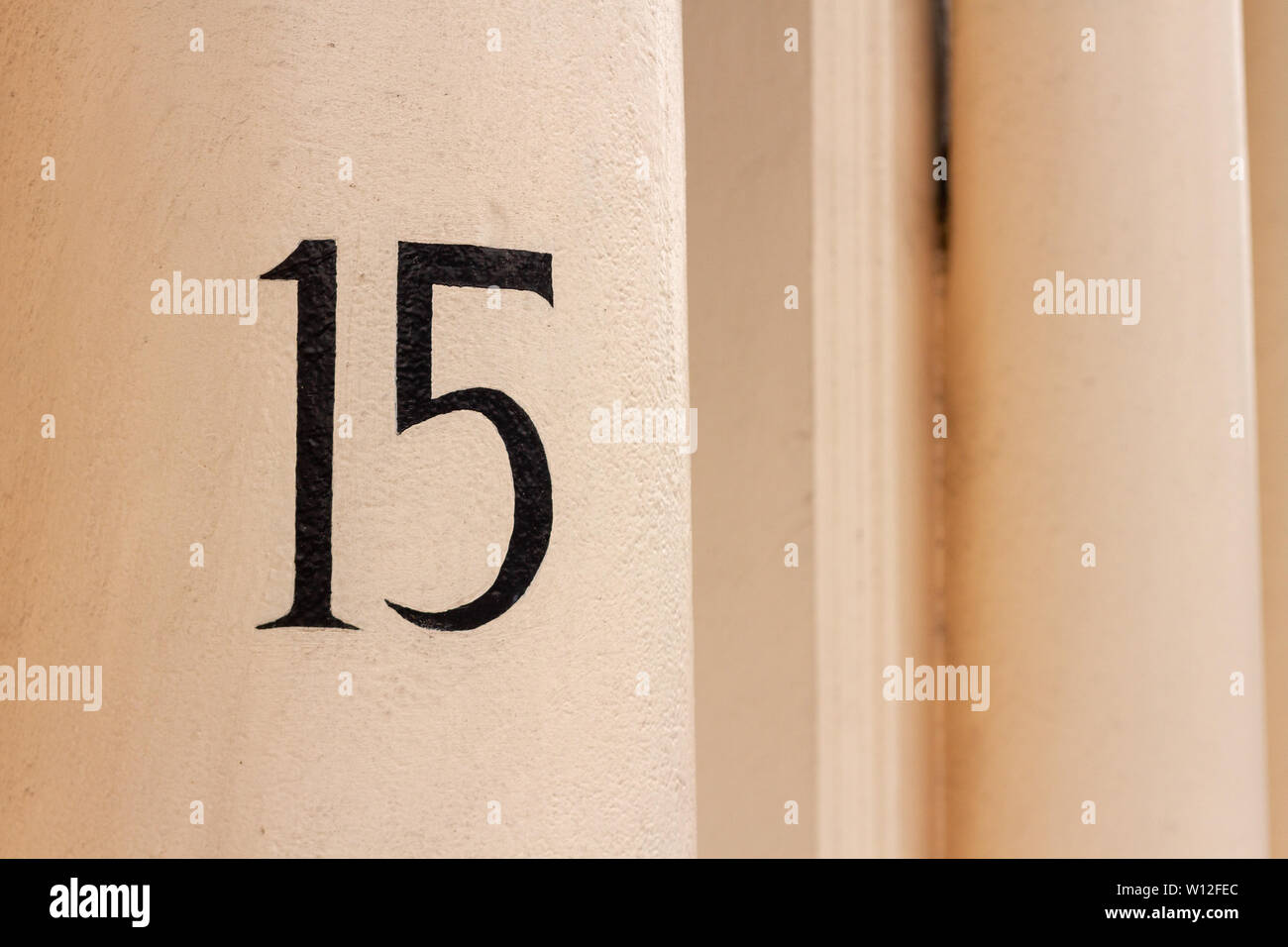 House number fifteen with the 15 in black on a stone pillar Stock Photo