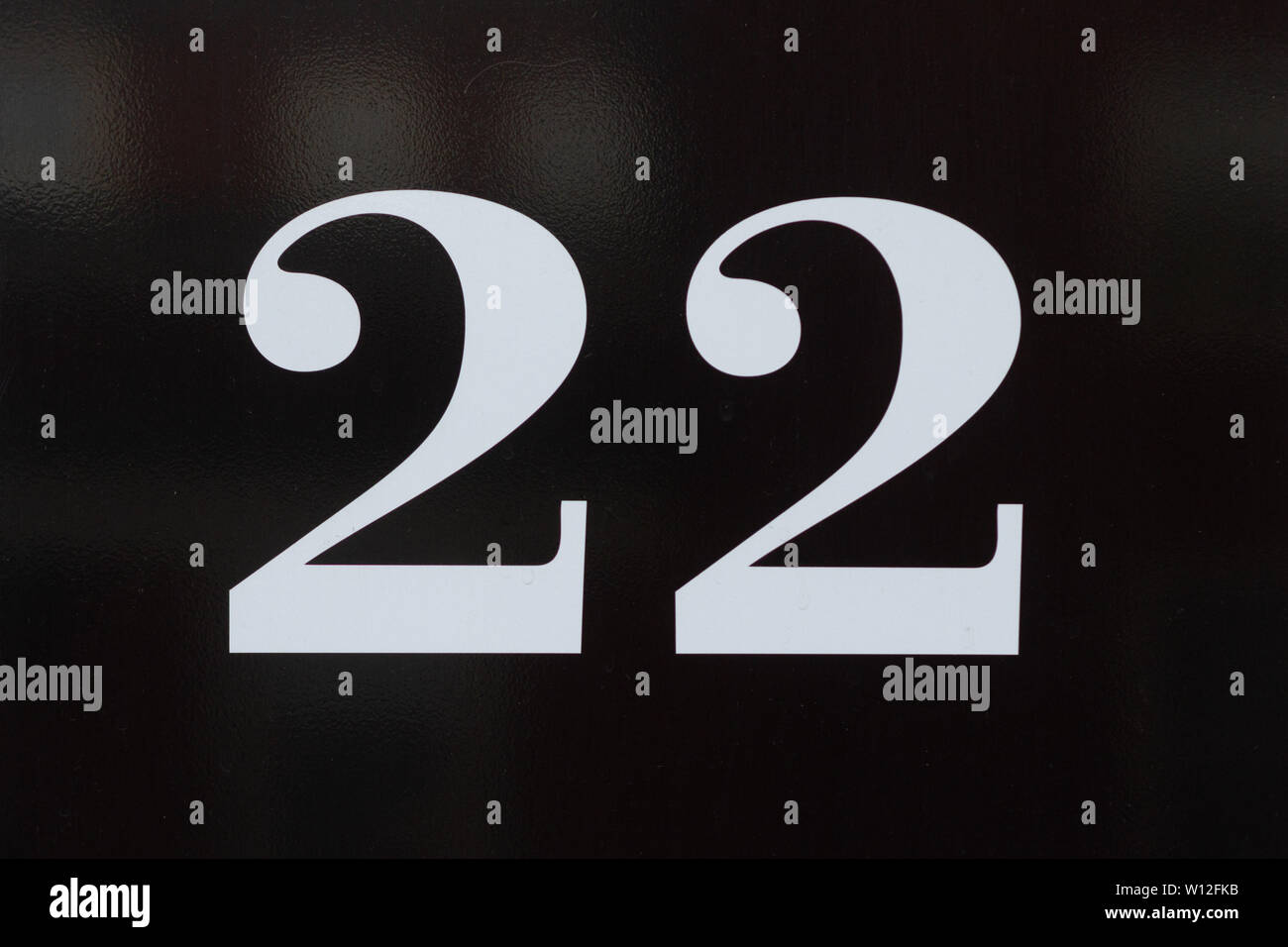 House number 22 in white curled lettering on a black shiny surface Stock Photo