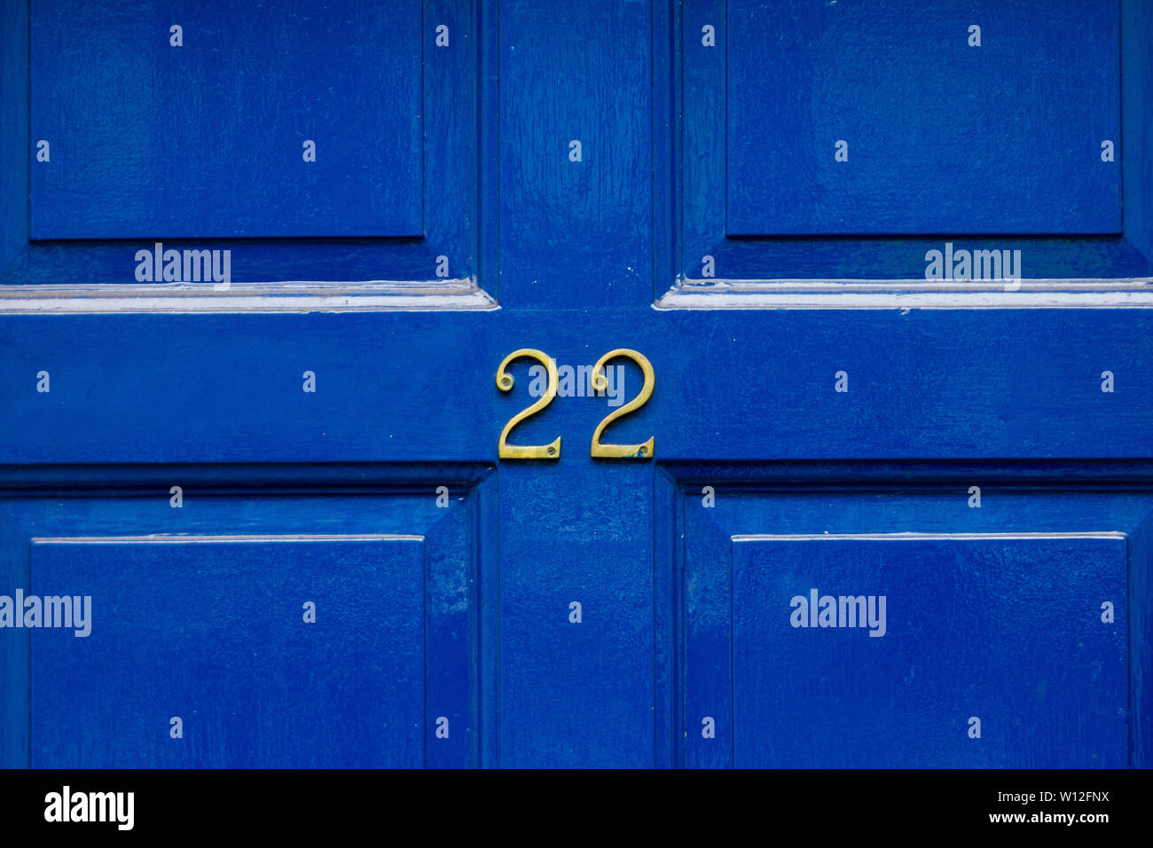 House number 22 with the twenty-two in the center of a bright blue carved front door Stock Photo