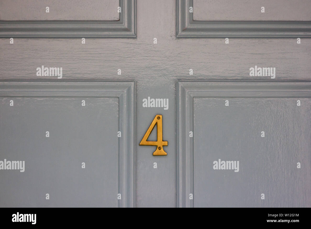 House number 4 in the lower section of a light grey door Stock Photo