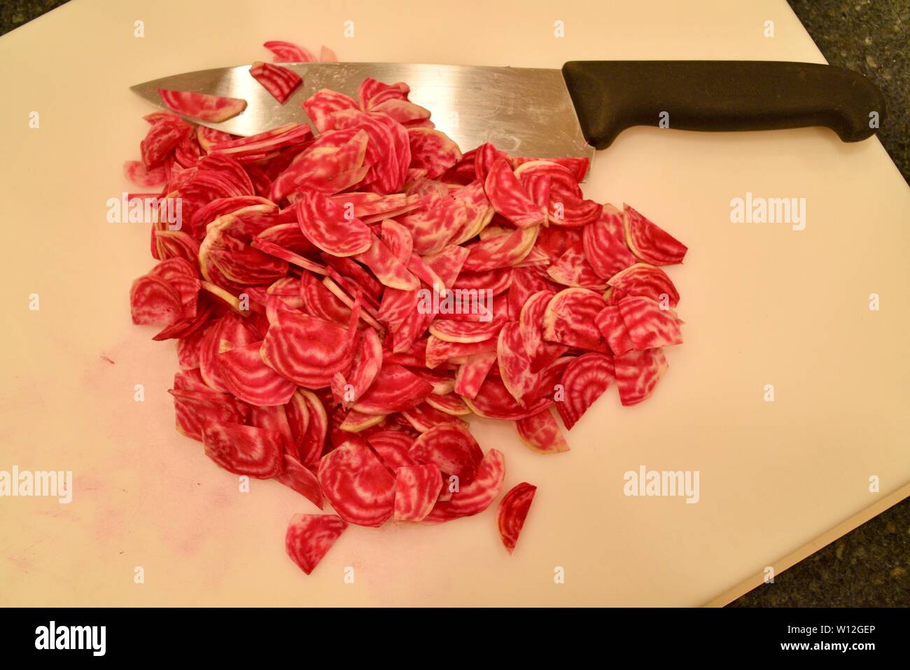 Sliced, farm fresh, bright red chioggia beets (beetroots) on a white cutting board, with knife, Wisconsin, USA. Stock Photo