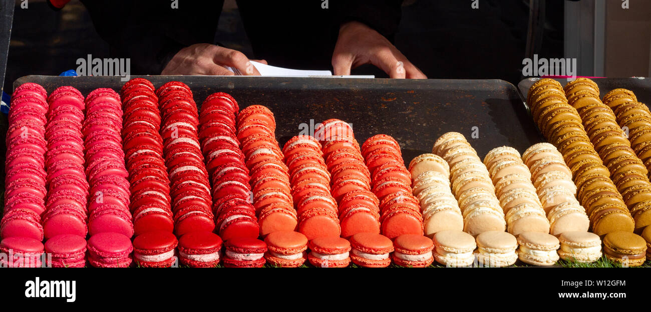 Fresh macarons arranged in colorful columns and rows, sorted precisely on a market stand Stock Photo