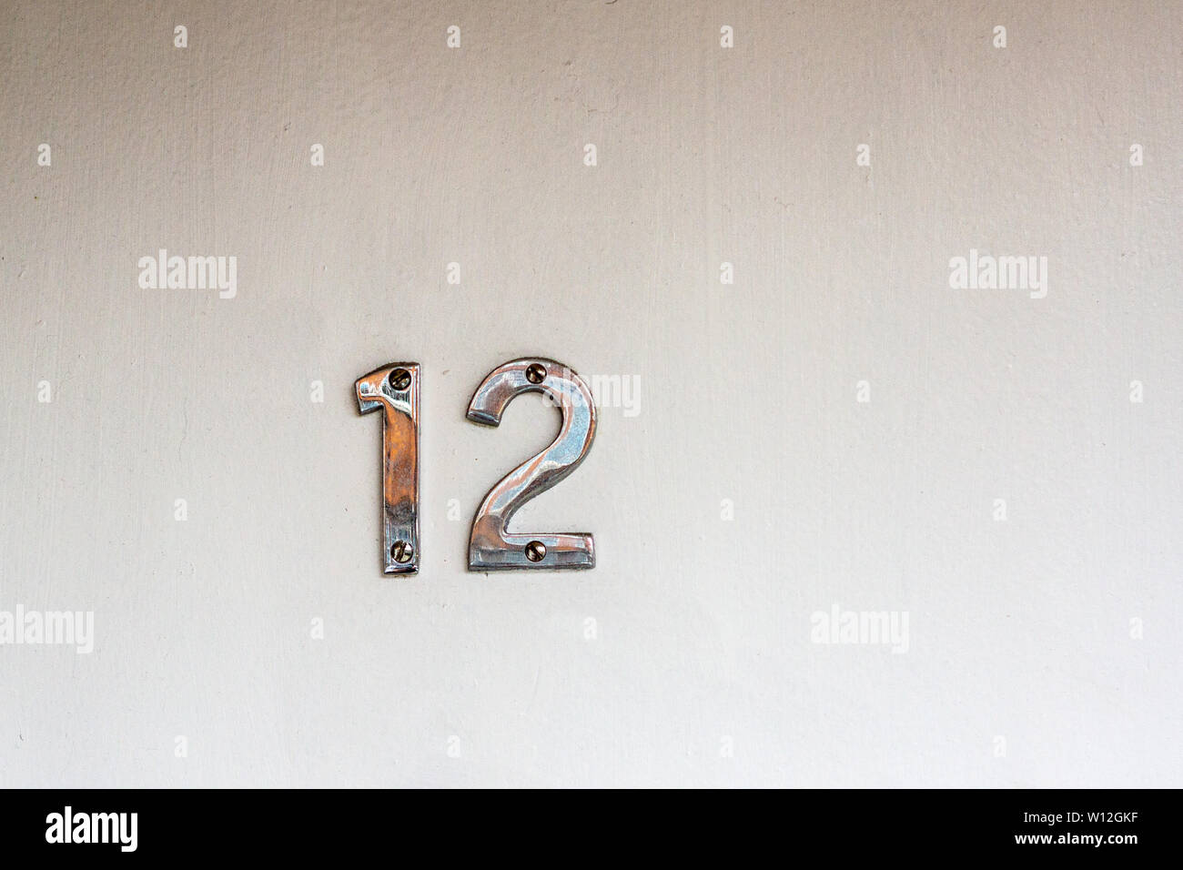House number 12 with the twelve in silver digits on a white surface Stock Photo