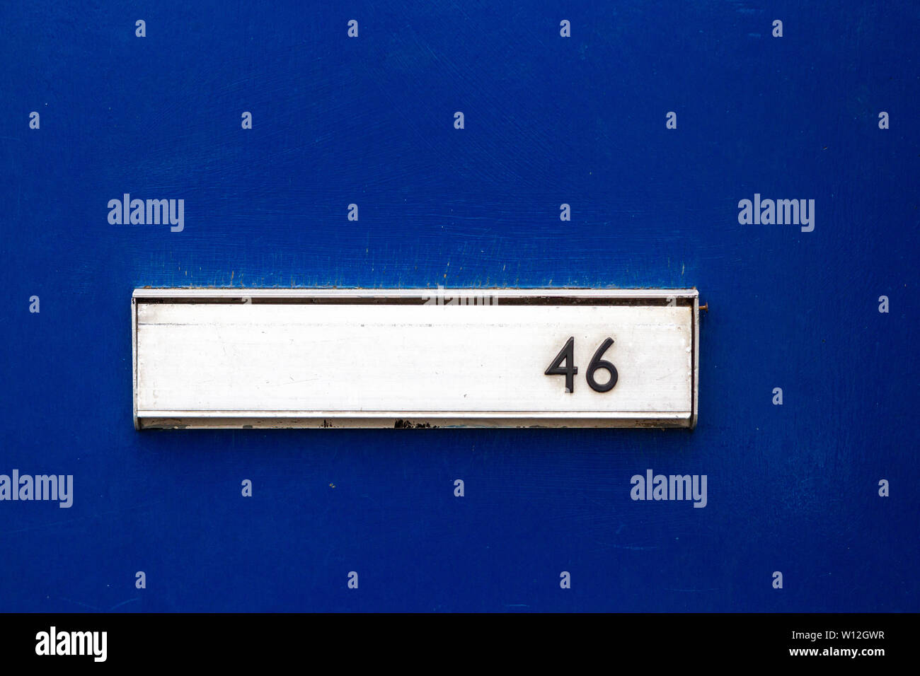 House number 46 with the forty-six in black on a silver letterbox set on a blue front door Stock Photo