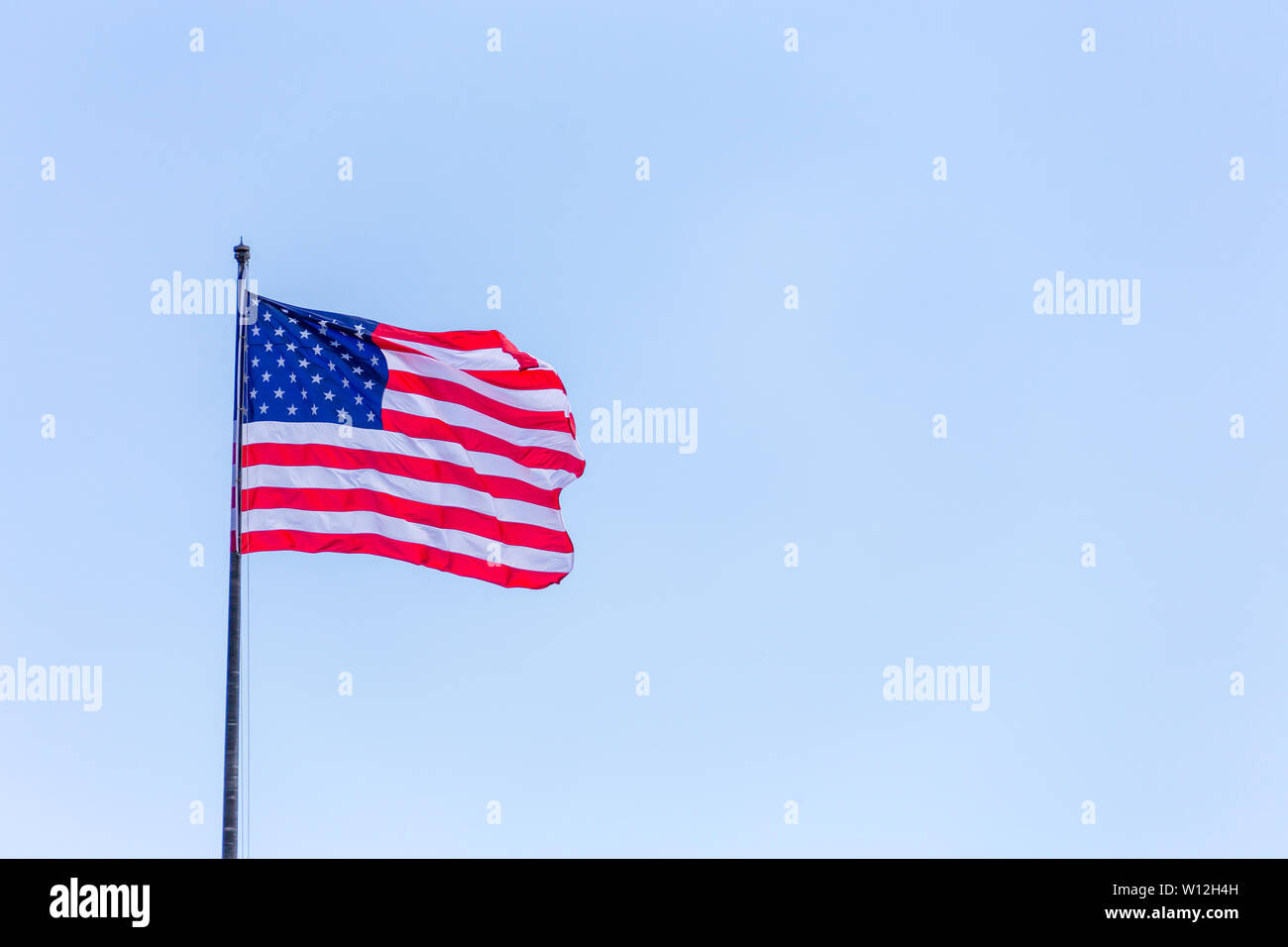 American flag on the blue sky on the wnd Stock Photo - Alamy