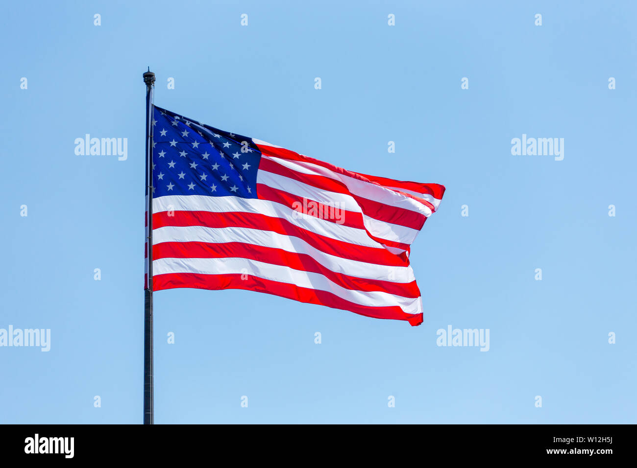 American flag on the blue sky on the wnd Stock Photo - Alamy