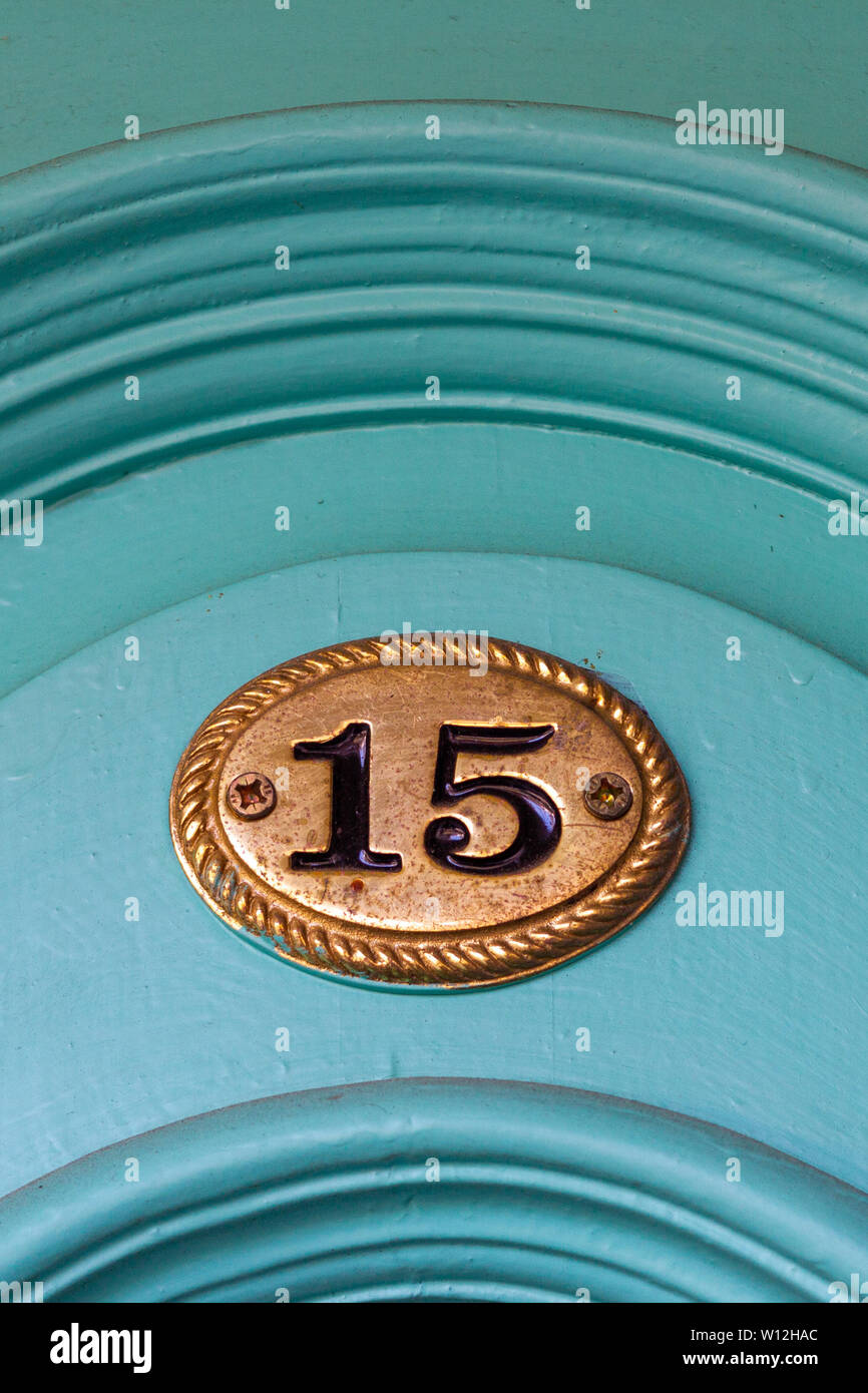 House number fifteen with the 15 on a bronze plaque on a turquoise curved door Stock Photo