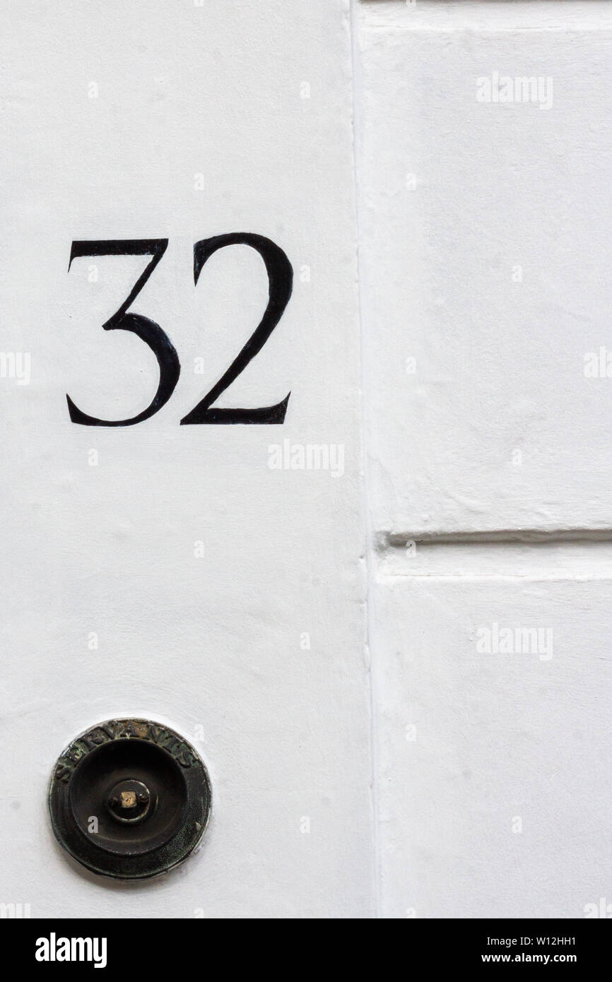 House number 32 with the thirty-two painted in black on a white wall Stock Photo
